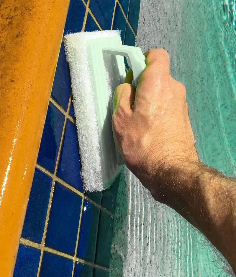 Person cleaning a pool edge with a scrubber