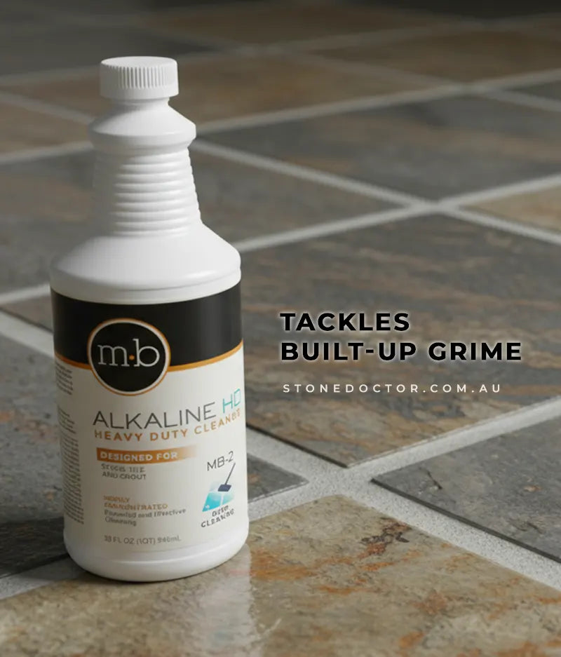 Bottle of m.b. Alkaline HD Heavy Duty Cleaner on a tiled floor with text 'Tackles Built-Up Grime' and 'stonedoctor.com.au'.