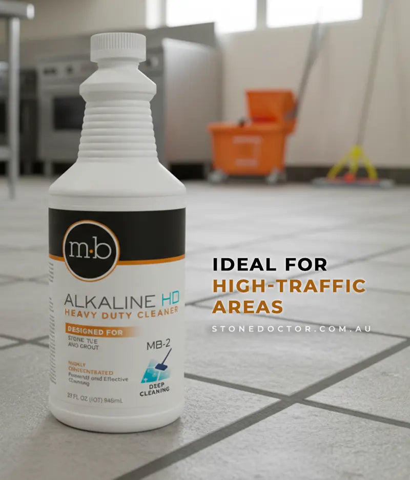 Bottle of M&B Alkaline HD Heavy Duty Cleaner on a tiled floor with cleaning equipment in the background.